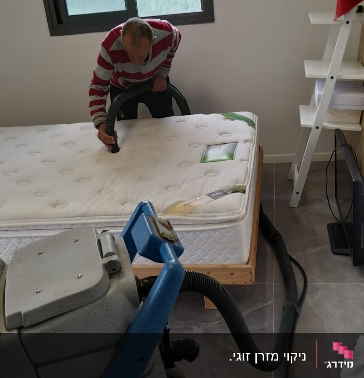 אדם מנקה מזרן עם שואב אבק תעשייתי